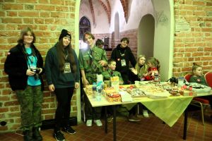 Wolontariusze stojąc przy stoisku ze słodyczami pozują do zdjęcia