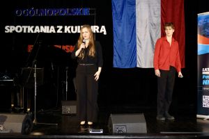 Wykonawczyni śpiewa, w tle młody mężczyzna