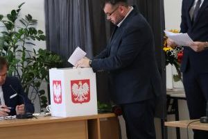 Radny wrzuca do urny kartę do głosowania