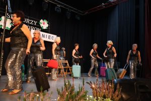 grupa seniorek na scenie z walizkami
