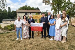 Delegacja Powiatu Nidzickiego trzymająca flagę Polski przy znaku Nidzica we Francji