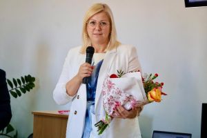 Skarbnik Miasta - Agnieszka Jastrzębowska z bukietem kwiatów i mikrofonem