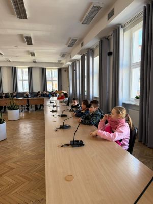 Uczniowie siedzą przy stole konferencyjnym