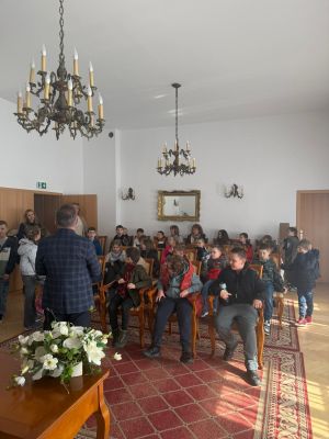 Uczniowie siedzą w fotelach na sali ślubów