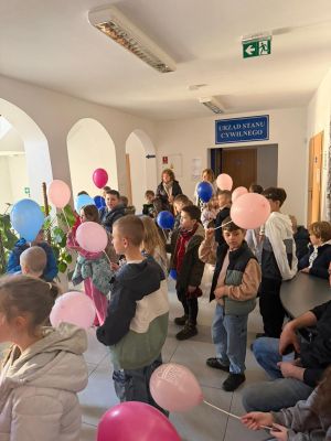 Uczniowie stoją na korytarzu trzymając kolorowe baloniki