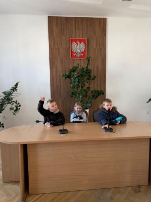 Troje uczniów siedzi przy stole konferencyjnym