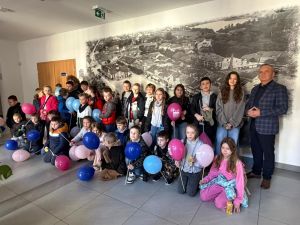 Uczniowie pozują do zdjęcia trzymając kolorowe baloniki